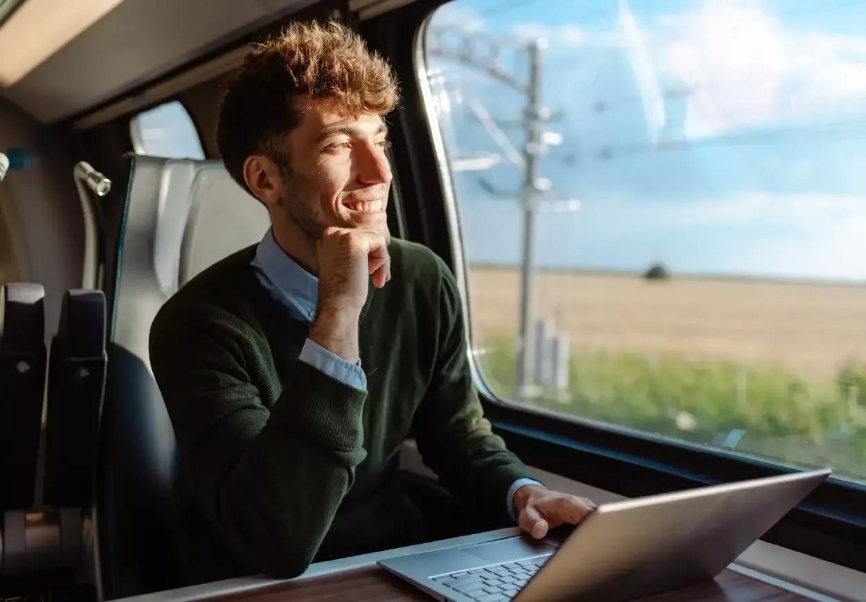 Man looking out train window experiencing bolt-on bank connectivity for ERPs on his laptop